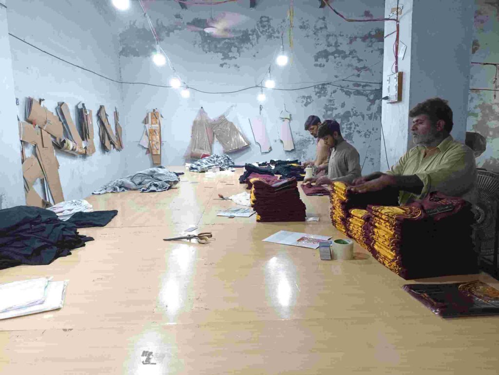 A fashion factory with individuals diligently working on sewing and designing clothes.